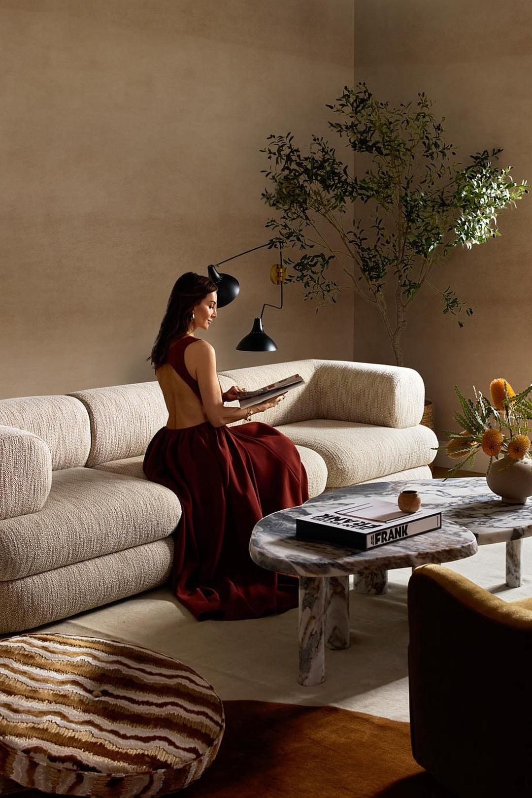 Ambiente elegante em tons terrosos com sofá claro e detalhes em vinho